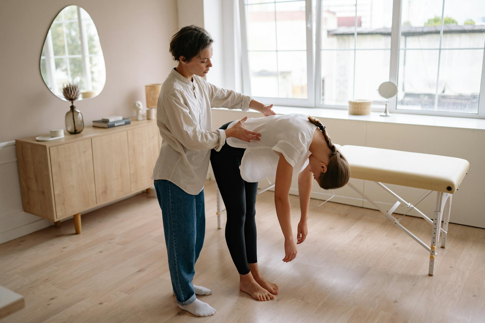 A therapist assists a client in a wellness session in a modern brightly lit room.